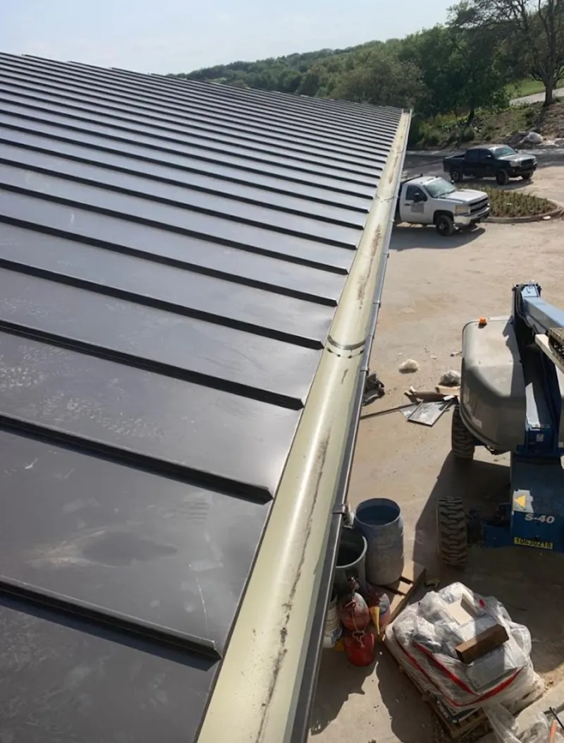 Standing seam panel and gutter detail on a metal roofing jobsite in Ayer